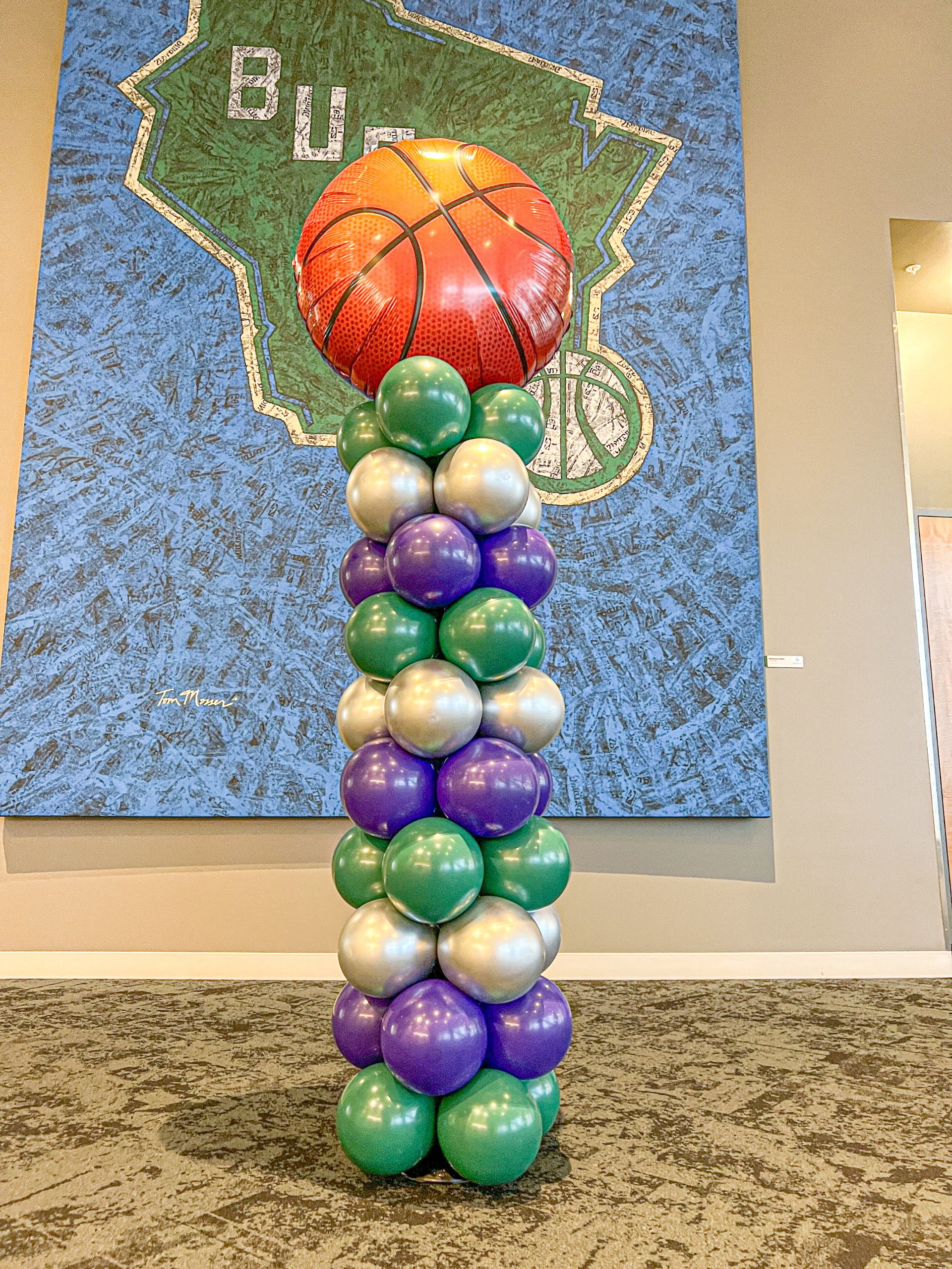 A classic style column using purple, green and silver with a large basketball topper balloon