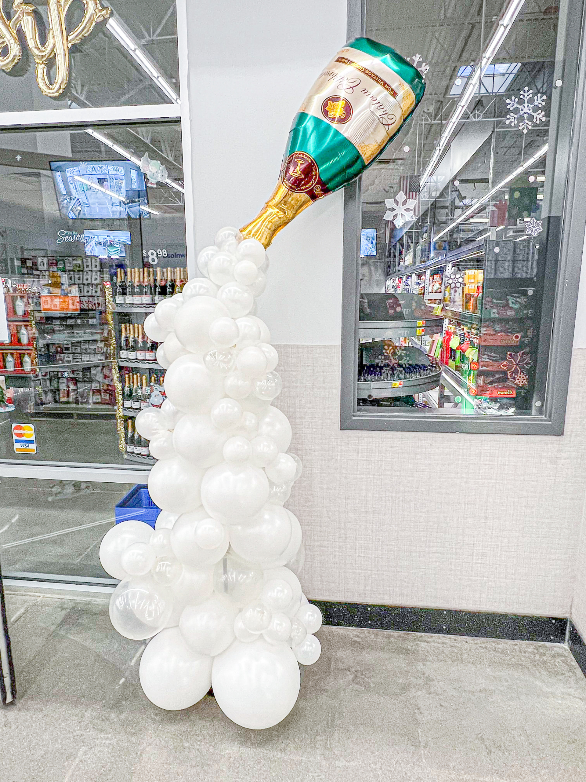 Custom balloon column with a champagne bottle on the top and balloons flowing out of the bottle mimicking a champagne flow